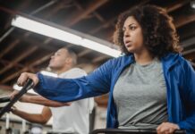 Zestresowana kobieta plus size na rowerku stacjonarnym obok wysportowanego mężcz